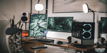 A clean and organized gaming setup with dual monitors displaying lush green foliage, a gaming PC, keyboard, mouse, and streaming peripherals, representative of a professional streamer's workspace like Maherco's.