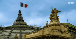 The French Tricolour flag flying atop a historic Parisian building (Grand Palais), representing the authority of the French gambling regulator, L’Autorité Nationale des Jeux (ANJ).