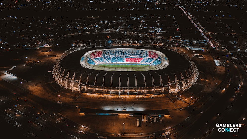 A wide aerial view of the Fortaleza stadium glowing at night, highlighting the massive infrastructure that relies on sponsorship revenue like the Cassino Bet deal.