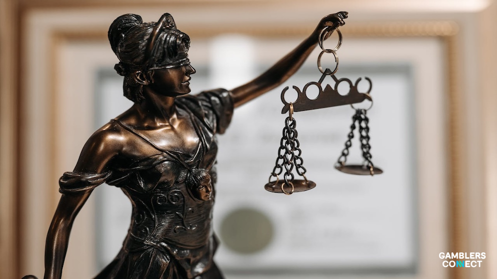 A close-up view of the scales held by a Lady Justice statue, illustrating the legal class action lawsuit and demand for accountability facing the Norsk Tipping monopoly.