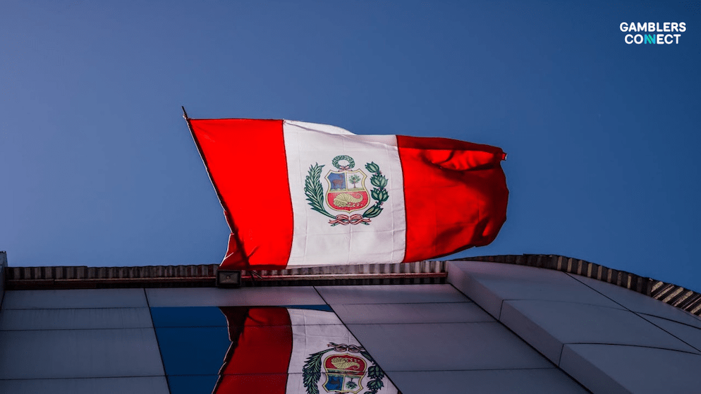 The flag of Peru flying on a modern building, representing the modernization of the country's betting market through digital payment solutions like PagoEfectivo.