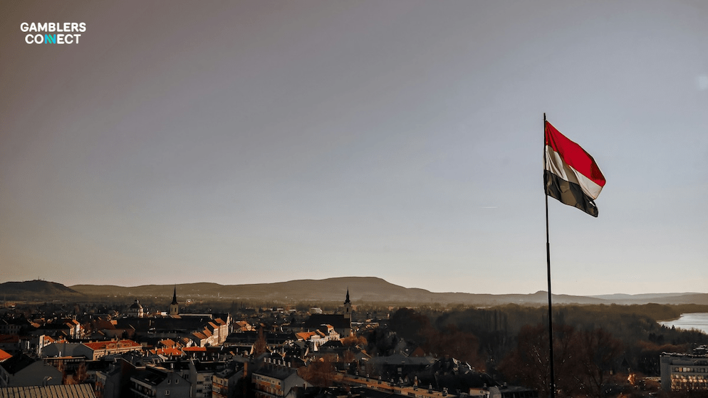 A panoramic view of a Hungarian city with the flag in the foreground, symbolizing the state's strict enforcement of gambling laws against unlicensed crypto platforms.