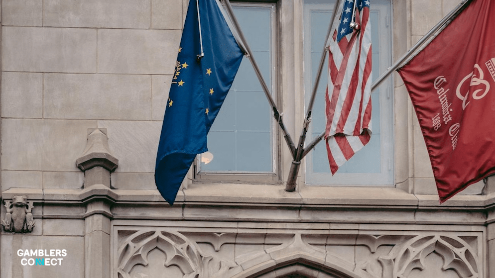 A detailed view of flags flying outside a government-style stone building in Indianapolis, representing the policy debate over gaming expansion.