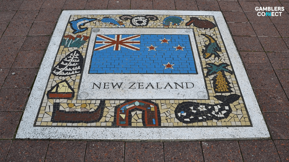 A detailed public floor mosaic displaying the text "NEW ZEALAND online gambling transformation" below the national flag, bordered by icons of local wildlife and culture.