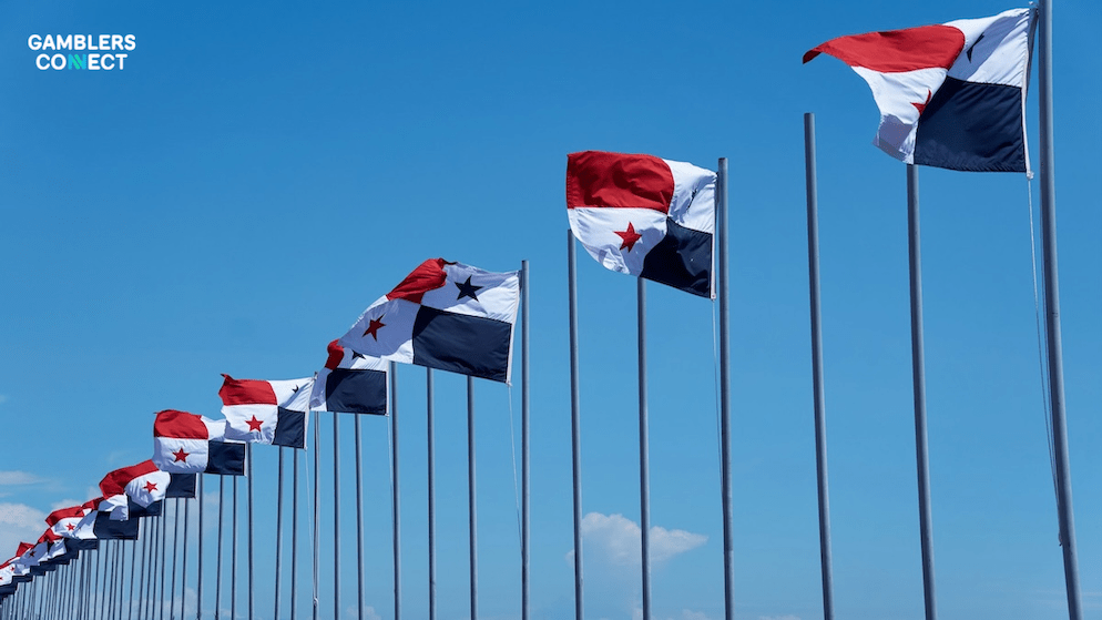 A long row of Panama national flags waving against a bright blue sky, symbolizing the transition of leadership at the Lotería Nacional de Beneficence.