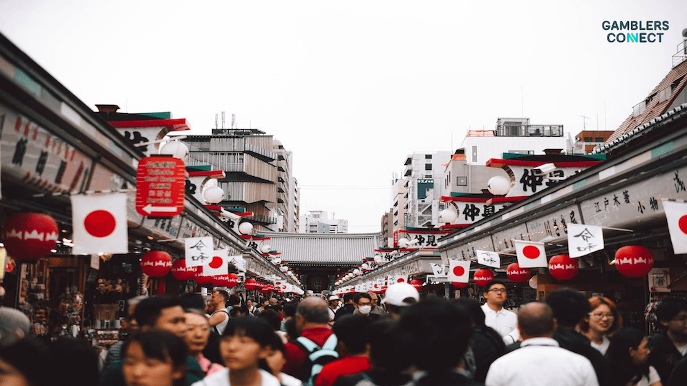 Crowds walking through a Japanese market street, symbolizing the balance between local community needs and the economic boost of a potential "Hokkaido-style" resort.