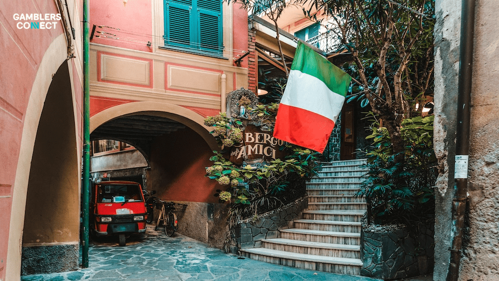 A view of a traditional Italian street with the national flag, representing the established regulatory environment of the ADM where Giochi24 has operated since 2008.