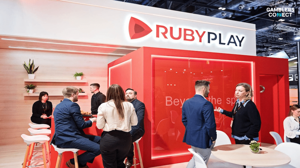 A side view of the RubyPlay booth showing professionals networking, symbolizing the collaborative and scalable nature of the new studio ecosystem.