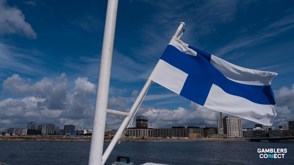 A scenic view of the flag of Finland over a harbor, symbolizing the end of the state's online gambling monopoly and the start of a new regulatory era with new license fee structure.