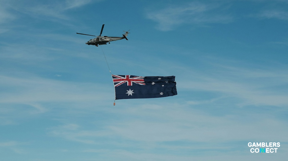 The Australian flag waving in front of a modern office building representing regulatory compliance and ACMA oversight.