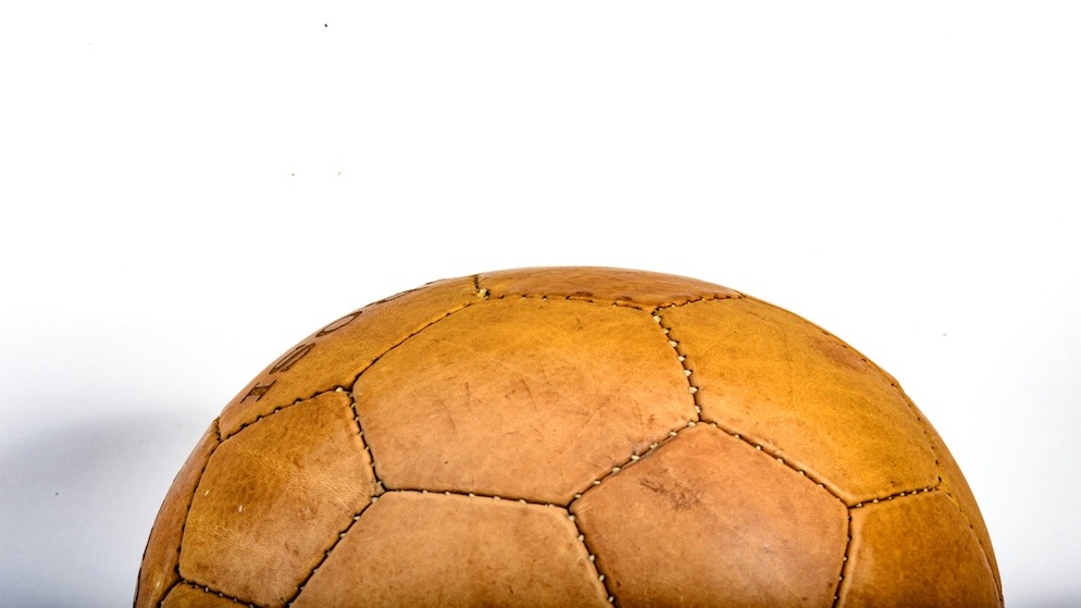 Comparison between the 18-panel brown leather ball from the inaugural 1955 European Cup and the thermally bonded 2026 Adidas Starball.