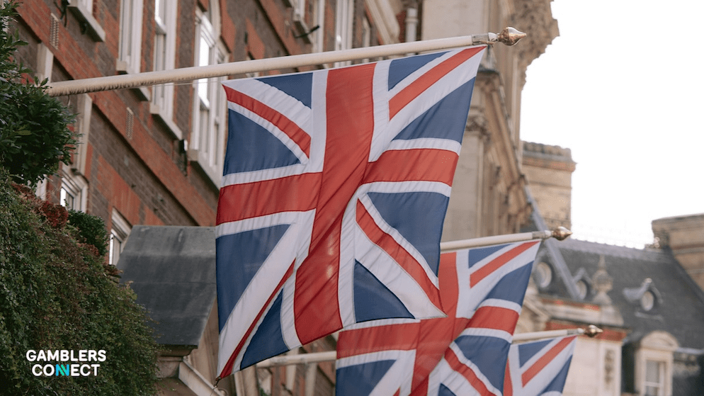 The Union Jack flag flying outside a brick government building in London, representing the British Gambling Commission's new consultation on fine allocation.